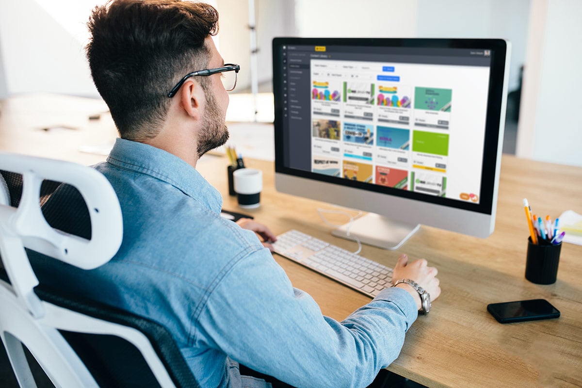 Dark-haired man is working with a computer at his desktop in office