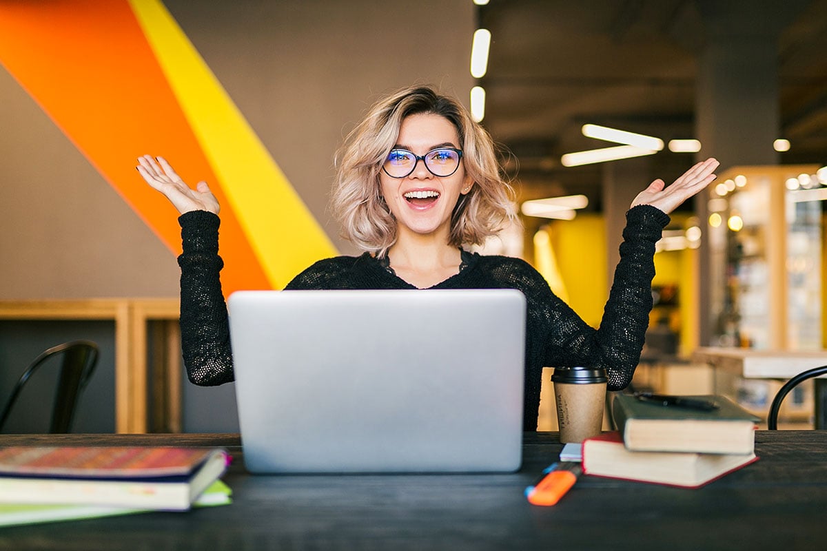 Woman at her desk, smiling with her hands raised Woman at her desk, smiling with her hands raised