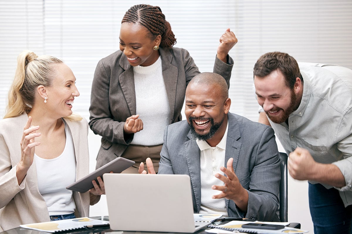 Excited employees celebrating around a laptop