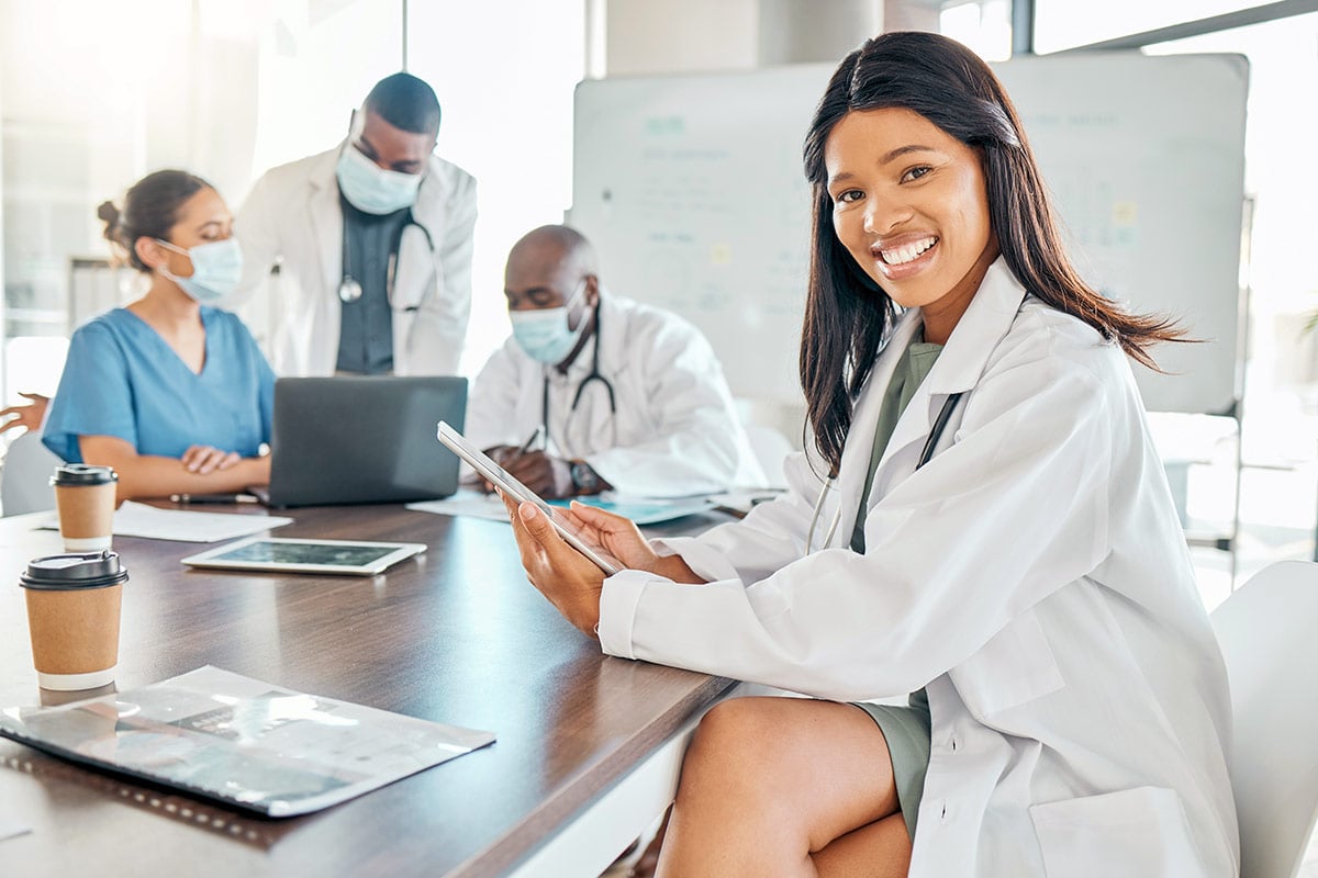 Woman doctor with tablet at meeting with team of doctors